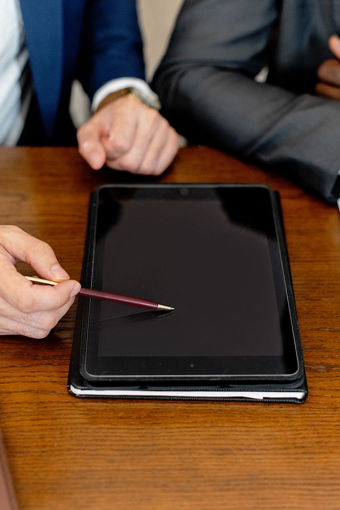 Business professionals using a digital tablet during a meeting, pointing with a pen on the screen.